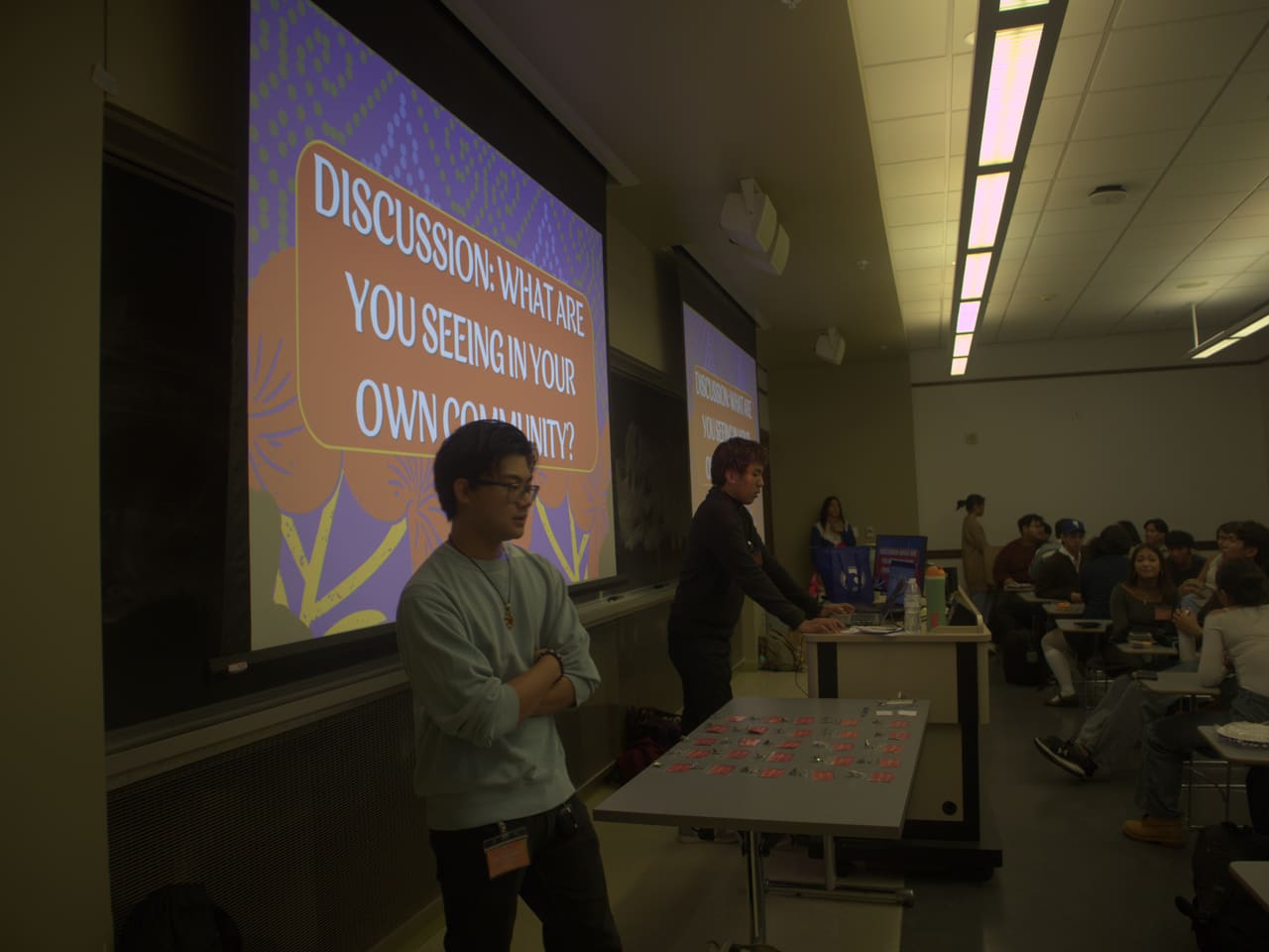 Facilitators leading a community discussion titled &ldquo;What are you seeing in your own community?&rdquo;